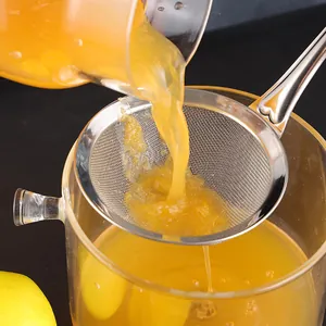 Stainless steel fine mesh strainer filtering orange juice into a glass jug