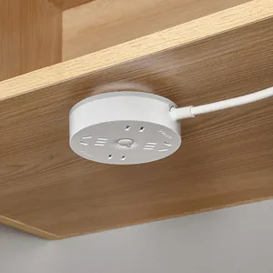 White circular adhesive power strip mounted under a wooden desk for efficient cable management