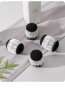 Detailed view of four white and black anti-tangling laundry balls arranged on grey fabric