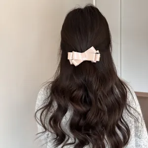 Elegant back view of a pink satin bow banana clip on long wavy brown hair styling