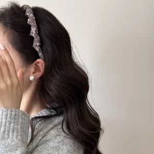 Close-up side view of a vintage floral fabric headband worn on long dark wavy hair.