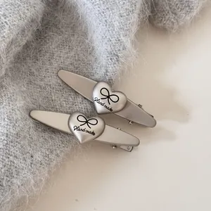 Primer plano de pinzas para el cabello plateadas con forma de corazón y texto