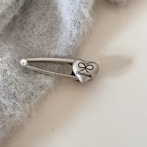 Primer plano de un pasador de pelo plateado con detalle de corazón, lazo y perla