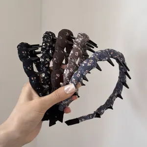 Hand holding a collection of vintage floral fabric wrapped headbands with inner teeth