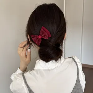 Close-up detail of a red polka dot bow hair clip styling a sweet Korean bun hairstyle