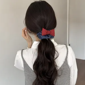 Dettaglio di un elastico per capelli con fiocco in denim e rosso su una coda di cavallo