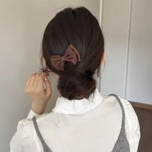 Close-up of a brown polka dot bow hair clip styling a neat bun on dark hair.