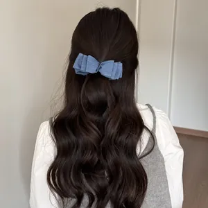 Dettaglio posteriore di un fermaglio per capelli a fiocco blu denim su lunghi capelli