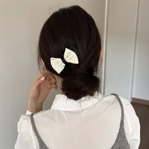 Detail showing a sweet cream polka dot bow hair comb accessory styled on a low bun hairstyle.