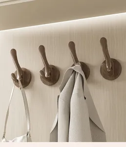 Detail view of walnut wood grain suction cup hooks holding a coat and a bag on wall.