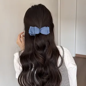 Vista posteriore di una donna con un fermaglio a fiocco in denim blu su capelli ondulati.