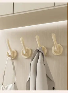 Modern wooden suction cup wall hooks shown with clothes and a bag in a home entryway
