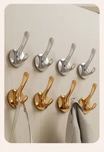 Close-up of gold and silver suction cup wall hooks on a light wood grain surface