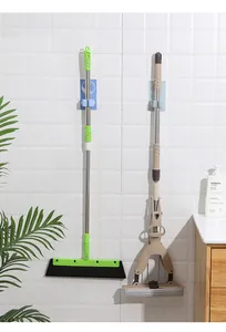 Close-up of adhesive wall-mounted mop and broom holders organizing cleaning tools on tiles