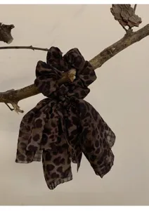 Chouchou léopard vintage avec longs rubans en forme de nœud exposé sur une branche rustique