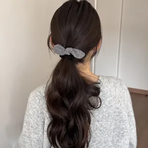 Achteraanzicht van een grijze polkadot strik scrunchie gebruikt voor een paardenstaart kapsel
