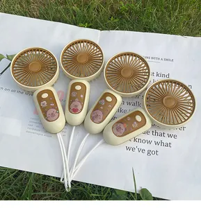 Set of handheld USB rechargeable mini fans with cute bear stickers on grass background