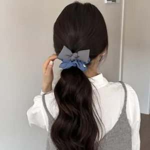 Primo piano di un elegante elastico per capelli con fiocco denim e grigio sulla coda