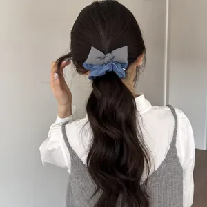 Elastico per capelli coreano in denim blu con fiocco grigio in una coda di cavallo