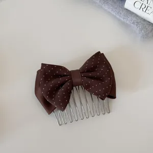 Detail view of a stylish brown polka dot bow hair comb with elegant silver metal teeth.