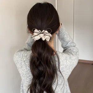 Sweet polka dot bow hair scrunchie shown in a low ponytail on wavy brown hair