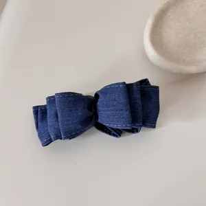 Dettaglio ravvicinato di una molletta per capelli in denim blu con cuciture bianche fini