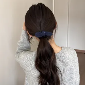 Achteraanzicht van een vrouw met een donkerblauwe haarelastiek met stippen en strik.