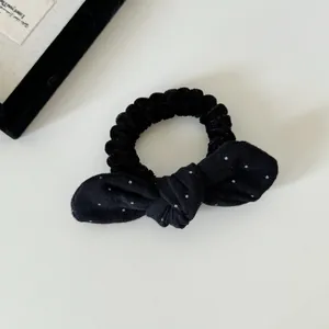 Detailopname van een zachte zwarte fluwelen scrunchie met een schattige witte stippenstrik