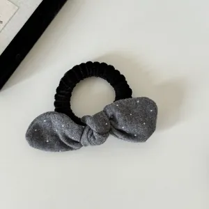 Gedetailleerde weergave van een zwart haarelastiekje met een grijze stippenstrik.