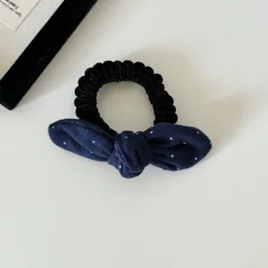 Gedetailleerd overzicht van een donkerblauwe gestippelde haarelastiek met zachte stof