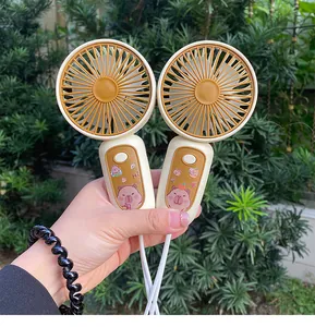 Two cute portable handheld USB rechargeable fans with capybara print being held outdoors