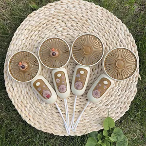 Four portable USB rechargeable mini fans with cute capybara stickers on a straw mat.