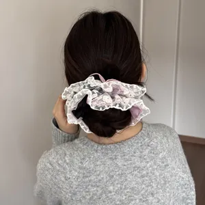 Elegant purple silk hair scrunchie with delicate white lace trim shown on a hair bun