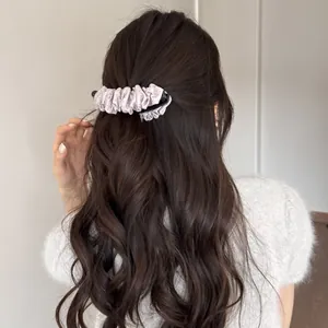 Détail d'une pince banane à pois plissée portée sur de longs cheveux ondulés