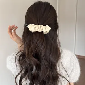 Vue arrière détaillée d'une pince banane à pois beige dans des cheveux ondulés