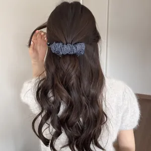 Pince à cheveux banane à pois style coréen portée sur de longs cheveux ondulés bruns