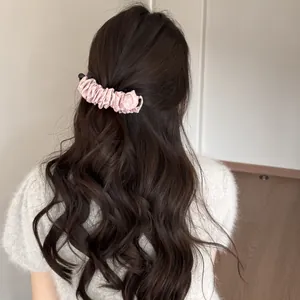 Détail d'une pince à cheveux banane à pois roses dans de longs cheveux ondulés