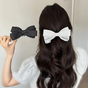 Detailansicht der schwarz-weißen gepunkteten Haarschleifen in gewelltem Haar.