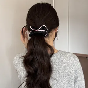 Detailed view of black polka dot scrunchie with pink ruffle trim on a low ponytail