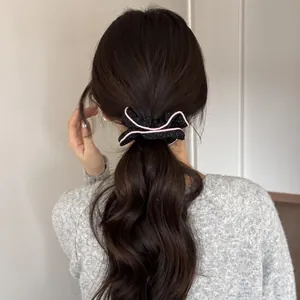 Close-up of a black polka dot leather bow scrunchie with pink edges on wavy hair