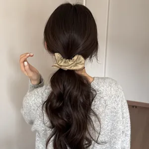 Detailed view of a stylish beige polka dot ruffle scrunchie worn in a low ponytail