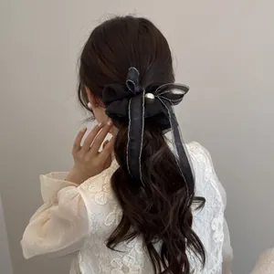 Detail view of an elegant black organza ribbon scrunchie with a pearl on a ponytail