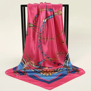 Gros plan d'un luxueux foulard carré en satin rose avec d'élégants motifs de chaînes