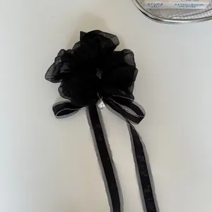 Detail shot of elegant black sheer scrunchie with ribbon ties and hanging pearl accessory