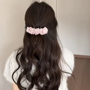 Pince banane rose à pois froissés maintenant des cheveux bruns ondulés, vue de dos
