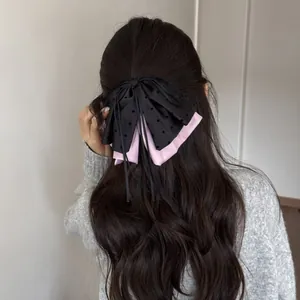 Detailed view of elegant black and pink ribbon bow hair clip styled on long wavy hair