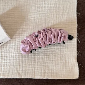 Vue détaillée d'une élégante pince banane rose à pois pour un coiffage élégant en queue de cheval