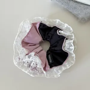 Detailed view of an elegant black and pink scrunchie with delicate white lace trim