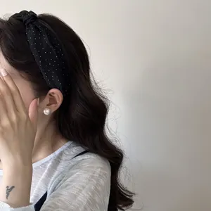 Dettaglio di un cerchietto per capelli a pois bianchi e neri indossato da modella