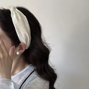 Dettaglio di un'elegante fascia bianca a pois per un look dai capelli alti